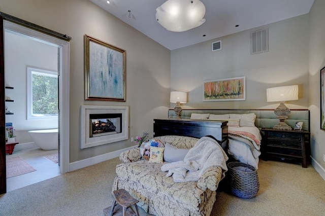 bedroom with ensuite bathroom and light colored carpet