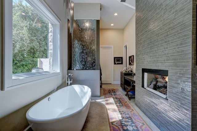 bathroom with a fireplace, plenty of natural light, vanity, and a bath