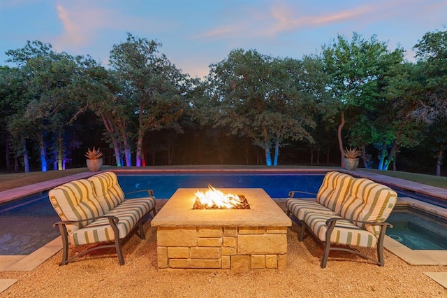 pool at dusk with a jacuzzi and an outdoor fire pit