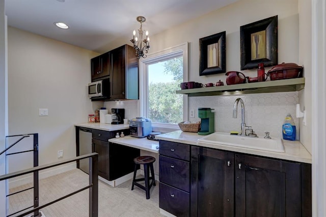 kitchen with pendant lighting, a notable chandelier, sink, dark brown cabinets, and stainless steel appliances