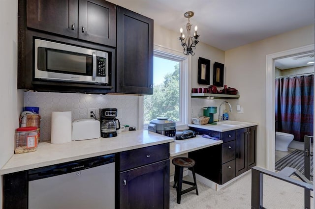 kitchen featuring sink, hanging light fixtures, a chandelier, light colored carpet, and appliances with stainless steel finishes