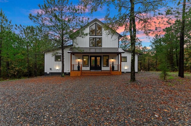 back house at dusk featuring covered porch