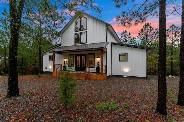 back house at dusk featuring a porch