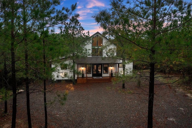 back house at dusk featuring covered porch