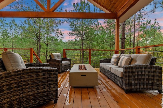 deck at dusk featuring an outdoor living space with a fire pit