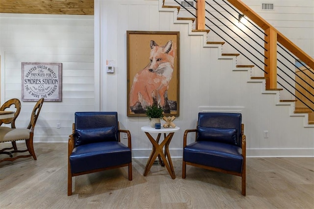 living area with wooden walls and wood-type flooring