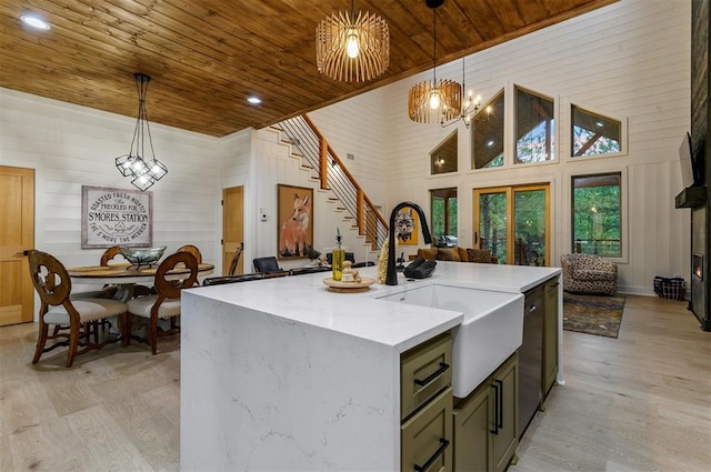 kitchen with pendant lighting, a kitchen island with sink, high vaulted ceiling, and light hardwood / wood-style flooring