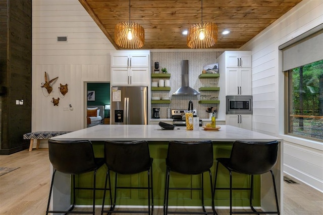 kitchen featuring wall chimney exhaust hood, plenty of natural light, white cabinets, and appliances with stainless steel finishes