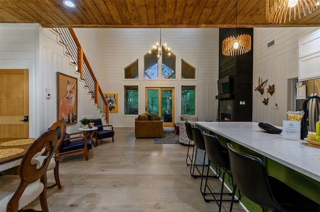 dining room featuring a high ceiling, an inviting chandelier, light hardwood / wood-style floors, wooden walls, and wood ceiling