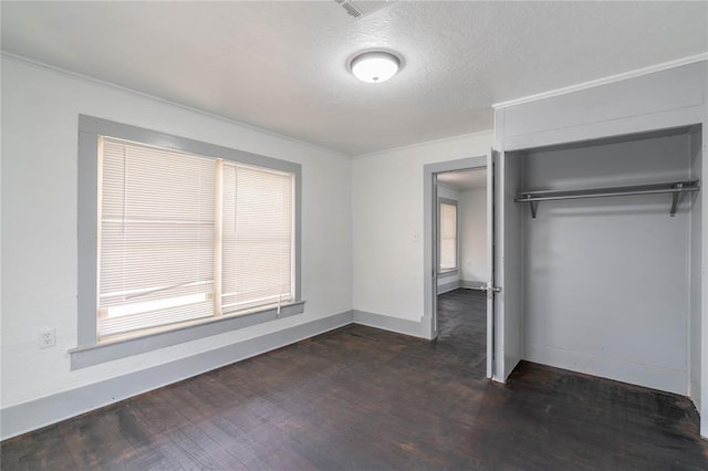 unfurnished bedroom with dark hardwood / wood-style floors, crown molding, a textured ceiling, and a closet