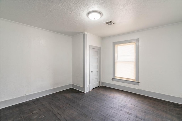 empty room with a textured ceiling, dark hardwood / wood-style flooring, and crown molding