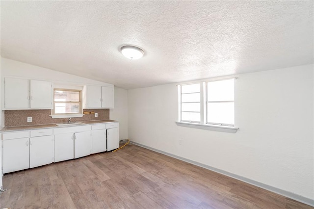 kitchen with white cabinetry, light hardwood / wood-style flooring, a textured ceiling, and sink