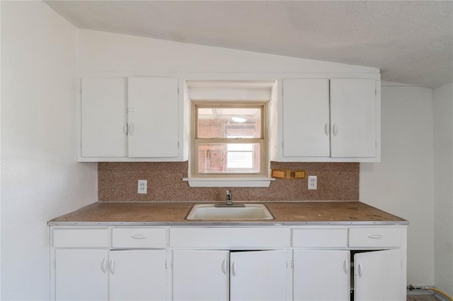 kitchen featuring white cabinetry, lofted ceiling, sink, and tasteful backsplash