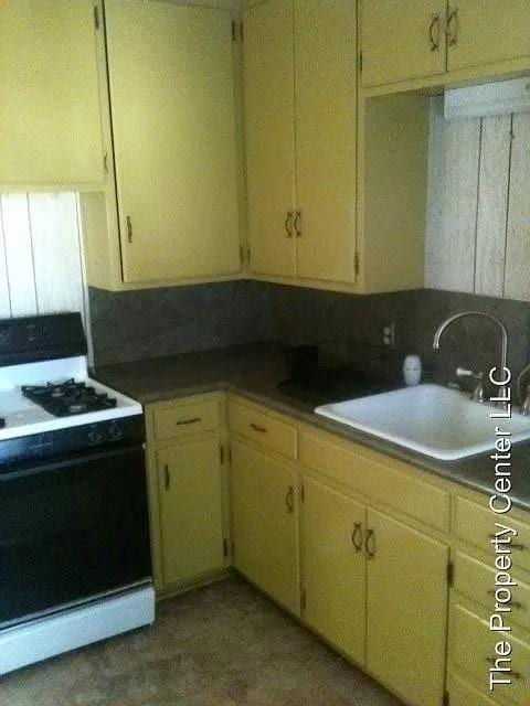 kitchen with cream cabinets, backsplash, white range with electric stovetop, and sink