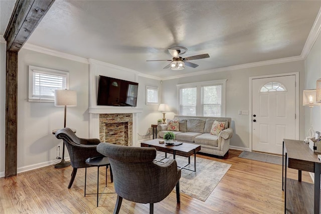 living room featuring a fireplace, light hardwood / wood-style flooring, ceiling fan, and ornamental molding