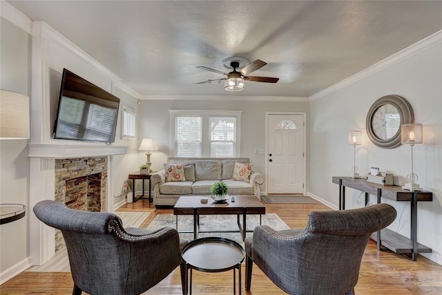 living room featuring a fireplace, crown molding, light hardwood / wood-style flooring, and ceiling fan