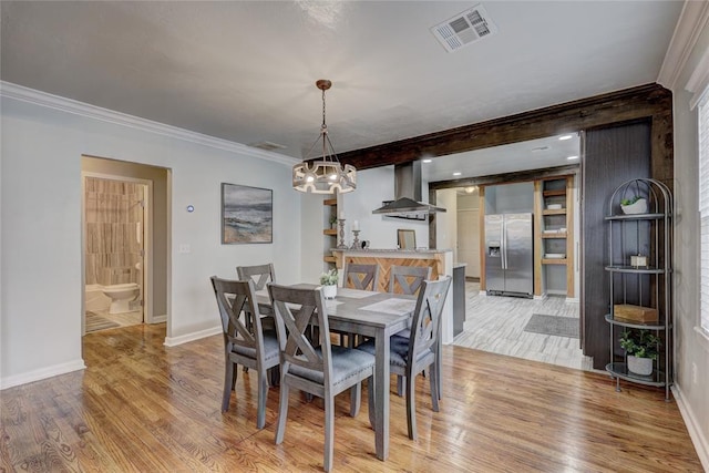 dining room with light hardwood / wood-style floors, crown molding, and an inviting chandelier