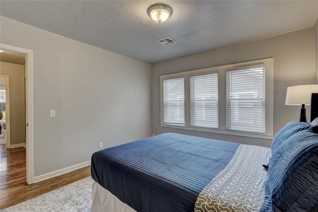 bedroom featuring a textured ceiling, hardwood / wood-style flooring, and multiple windows