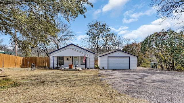 single story home featuring an outbuilding, a front lawn, covered porch, and a garage