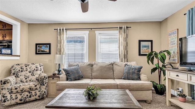 living room featuring ceiling fan, light colored carpet, and a textured ceiling