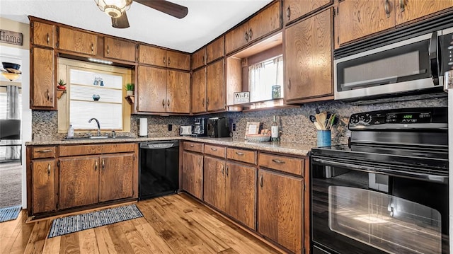 kitchen with black appliances, sink, decorative backsplash, ceiling fan, and light hardwood / wood-style floors