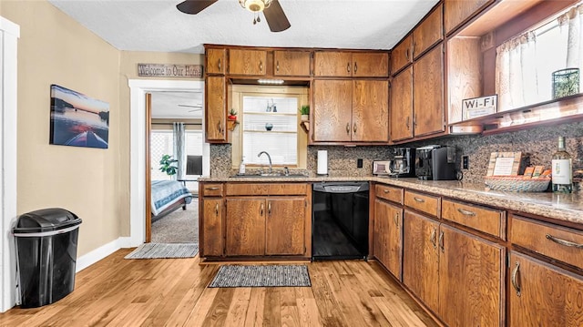 kitchen with plenty of natural light, sink, black dishwasher, and light hardwood / wood-style flooring