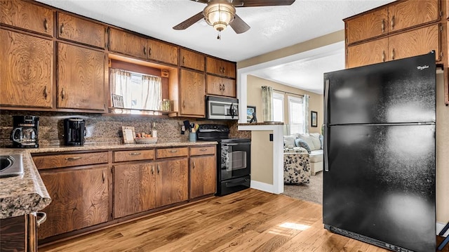 kitchen featuring tasteful backsplash, light hardwood / wood-style flooring, ceiling fan, and black appliances