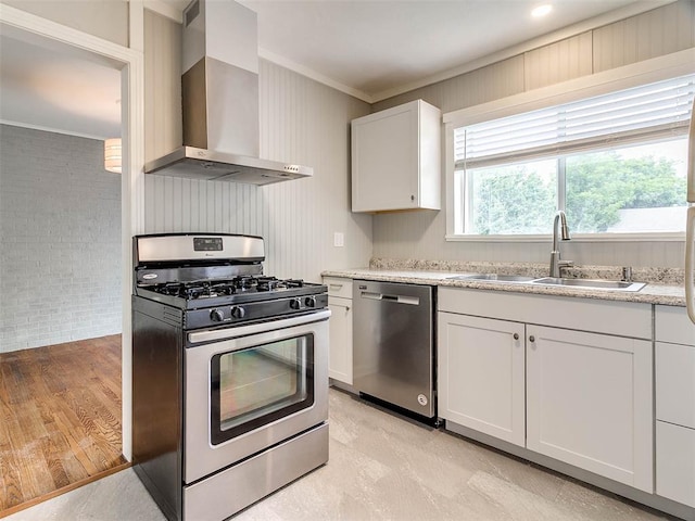 kitchen featuring stainless steel appliances, sink, wall chimney range hood, white cabinets, and light hardwood / wood-style floors