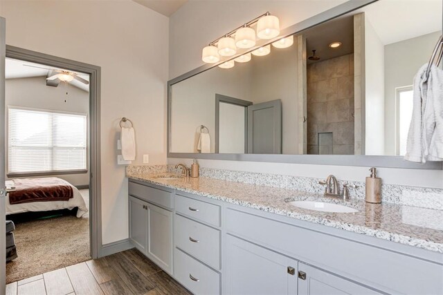 bathroom with ceiling fan, wood-type flooring, vaulted ceiling, tiled shower, and vanity