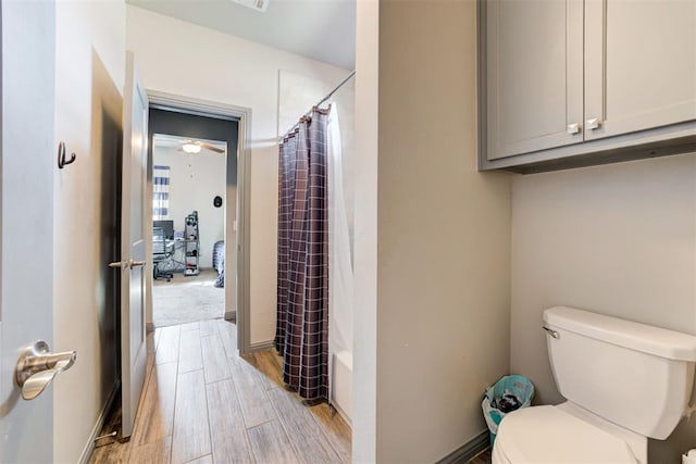 bathroom featuring shower / bath combo with shower curtain, toilet, and wood-type flooring