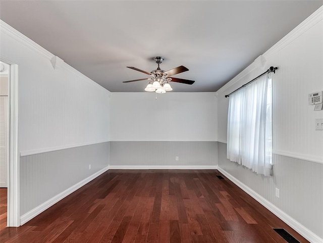 spare room featuring ceiling fan, wood walls, crown molding, and dark wood-type flooring