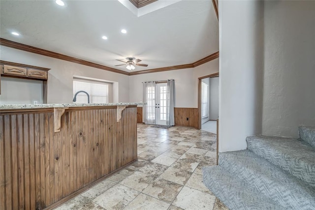 kitchen with french doors, ceiling fan, ornamental molding, kitchen peninsula, and a breakfast bar area