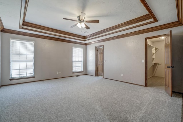 carpeted spare room featuring a tray ceiling, ceiling fan, and ornamental molding