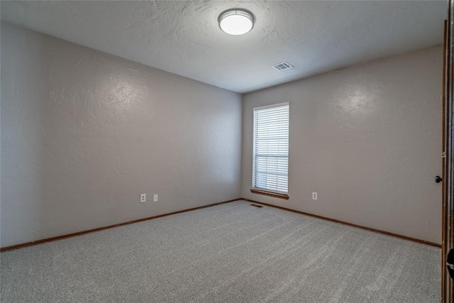 carpeted empty room featuring a textured ceiling