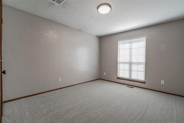 unfurnished room with carpet and a textured ceiling