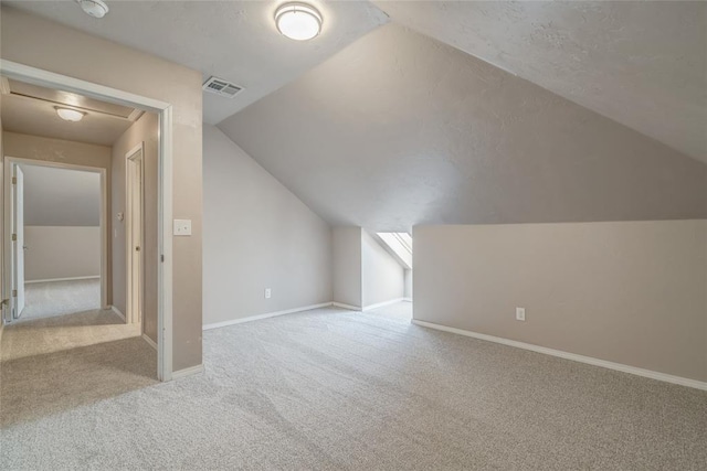 bonus room with light carpet and vaulted ceiling