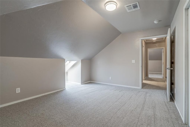 additional living space featuring light colored carpet and vaulted ceiling