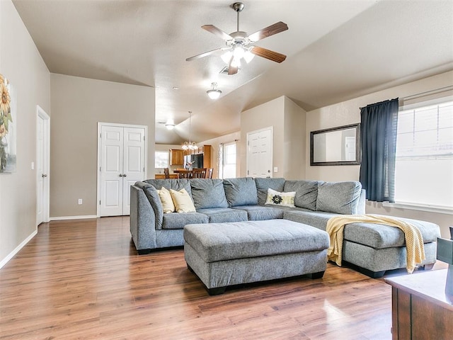 living room with hardwood / wood-style floors, ceiling fan with notable chandelier, and lofted ceiling