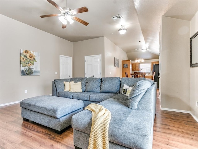 living room with ceiling fan with notable chandelier, lofted ceiling, and hardwood / wood-style flooring