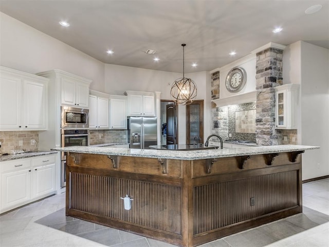 kitchen featuring a large island, white cabinetry, stainless steel appliances, and hanging light fixtures