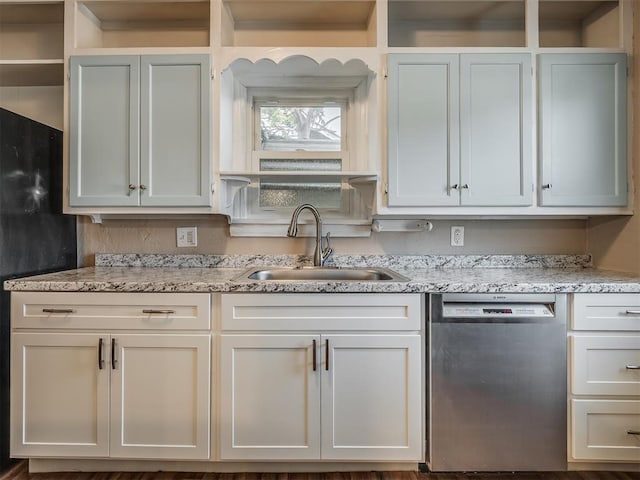 kitchen featuring stainless steel dishwasher, white cabinets, light stone countertops, and sink