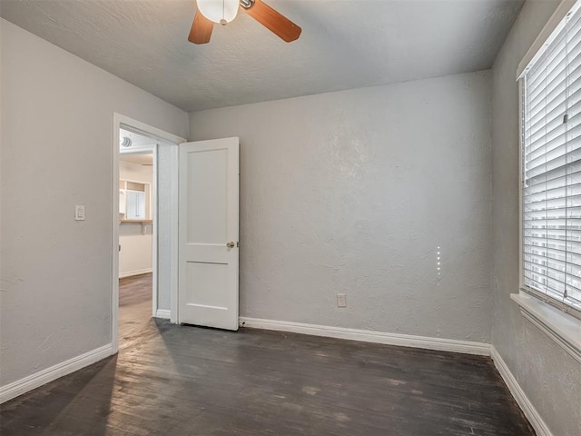 unfurnished room featuring a wealth of natural light, ceiling fan, and dark hardwood / wood-style floors