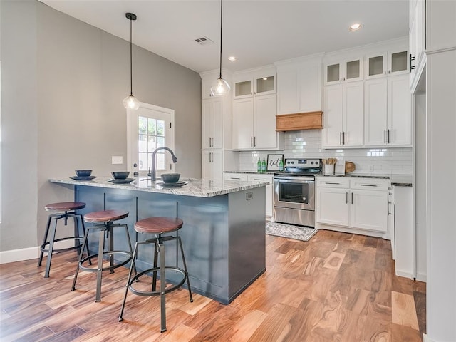 kitchen with electric range, light hardwood / wood-style flooring, white cabinets, and pendant lighting