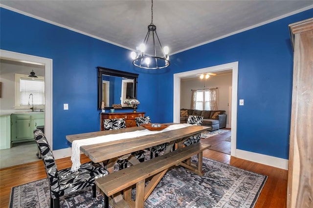 dining space featuring a chandelier, dark hardwood / wood-style flooring, ornamental molding, and sink