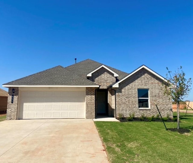 541 Park Pl, Newcastle, OK 73065 - view of front facade with an attached garage, concrete driveway, a front yard, brick siding, and a shingled roof