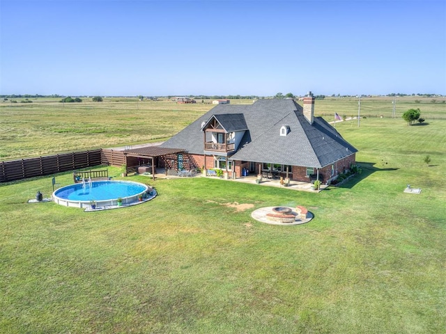 back of house featuring a balcony, a rural view, an outdoor fire pit, a patio, and a fenced in pool