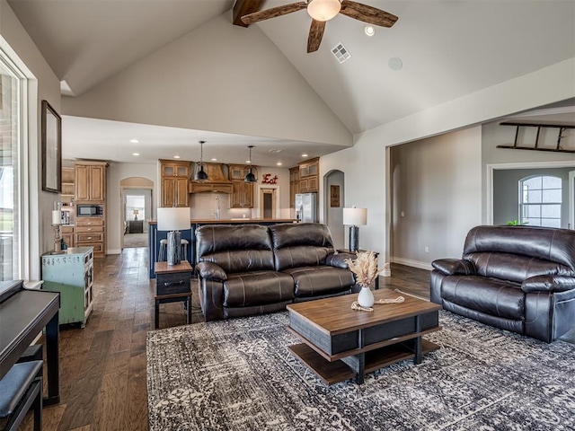 living room featuring ceiling fan, beamed ceiling, high vaulted ceiling, and dark wood-type flooring