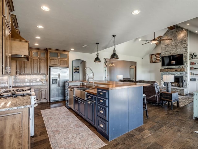 kitchen with sink, decorative light fixtures, dark hardwood / wood-style flooring, an island with sink, and stainless steel appliances