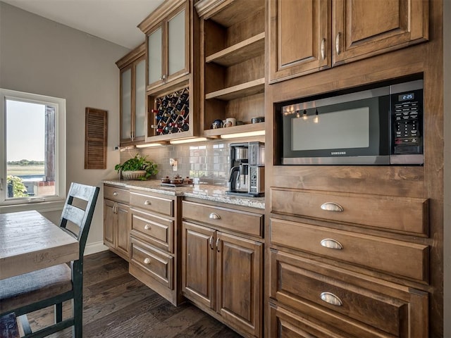 kitchen featuring tasteful backsplash, dark hardwood / wood-style floors, and light stone countertops