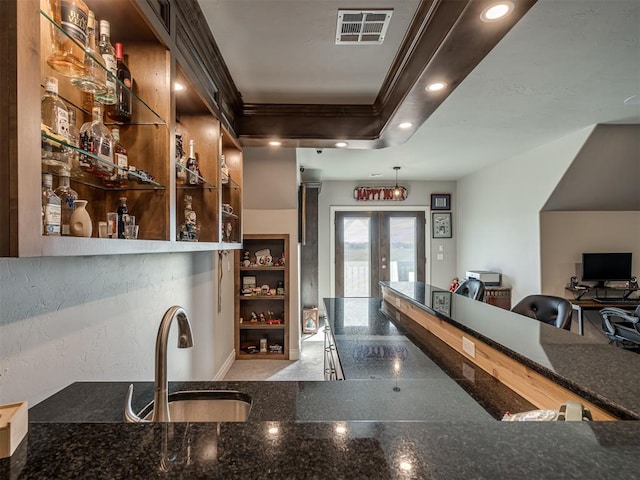 bar with ornamental molding, sink, dark stone counters, and french doors